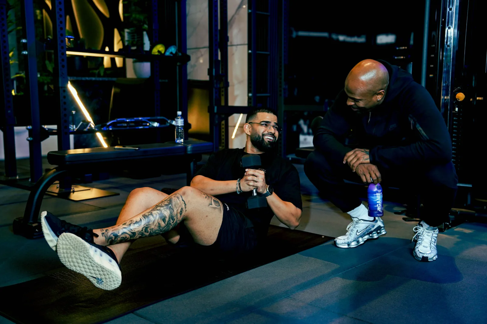 Savage-coach in gesprek met een lid tussen de sets op de trainingsmat