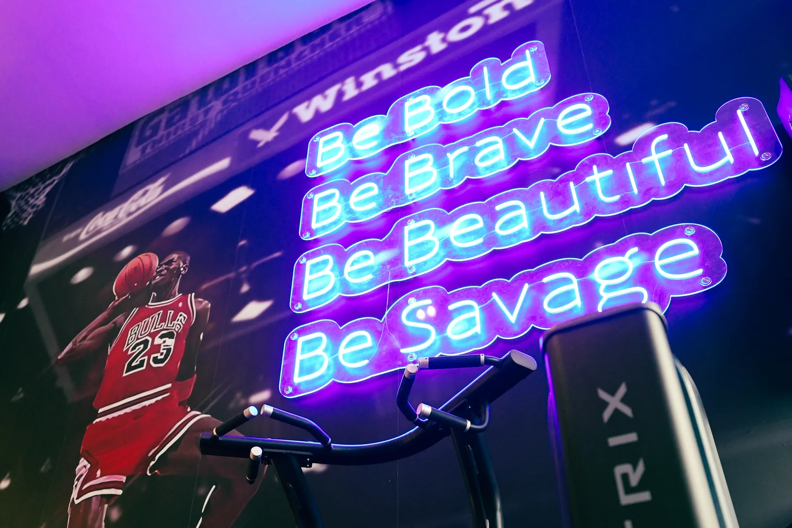 Neon manifestwand Be Bold, Be Brave, Be Beautiful, Be Savage boven de trainingsvloer