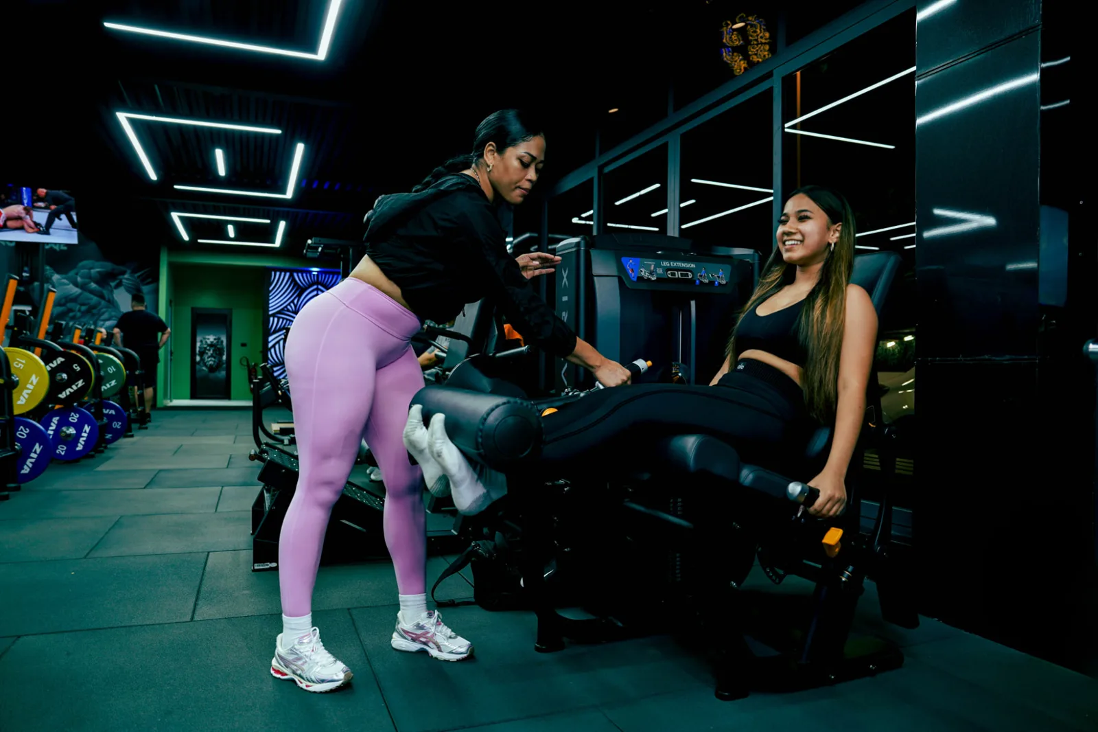 Savage-coach begeleidt een lid door een set op de leg extension-machine