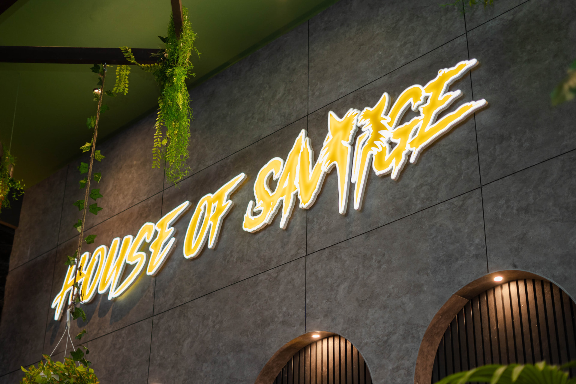 House of Savage illuminated wordmark on the club wall