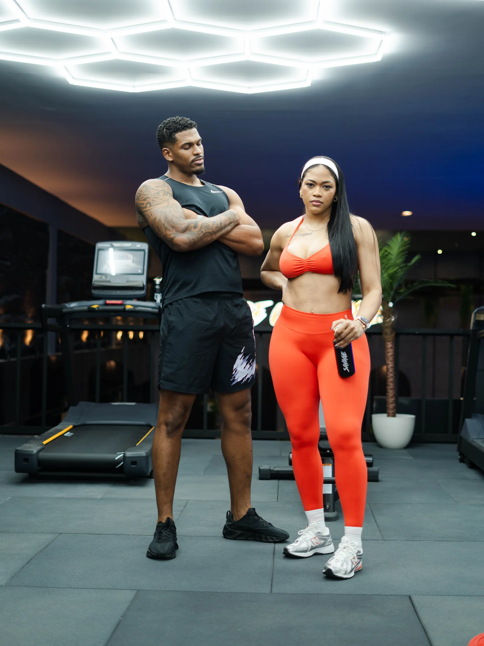 Twee leden van Savage Elite Fitness op de trainingsvloer onder de kenmerkende hexagonverlichting